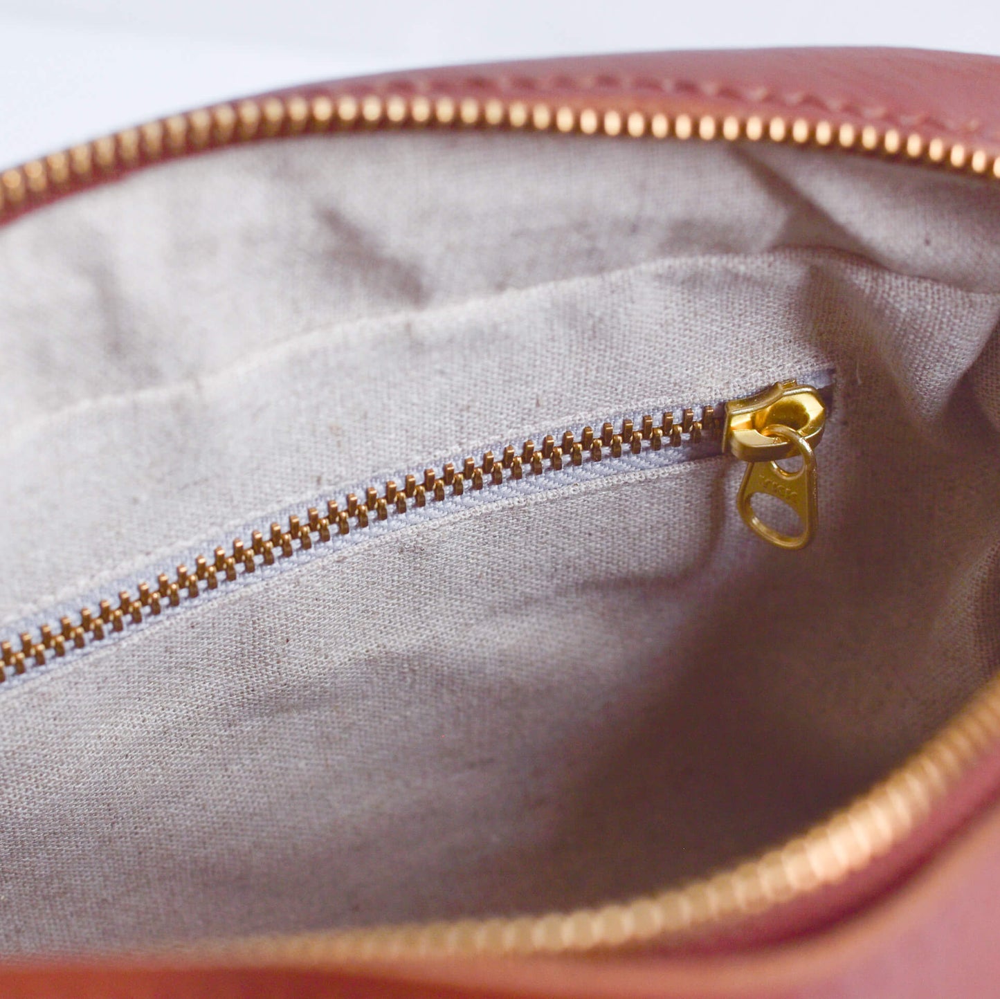 Close-up of a pink pouch with gold zipper and gold zipper pull.