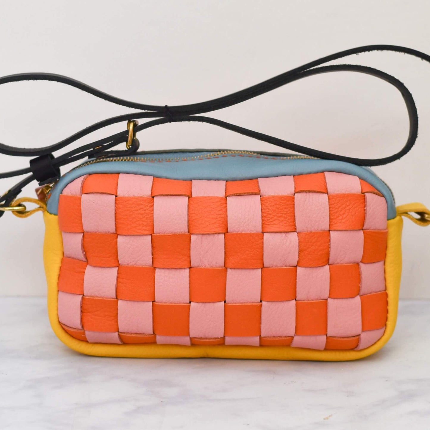Woven handbag with orange, pink, and yellow pattern on a white background