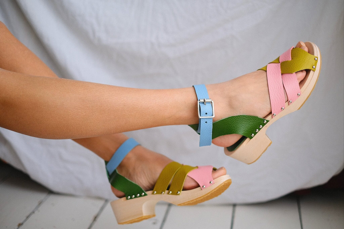 women's legs wearing a bright pair of colourful clog sandals against a white background
