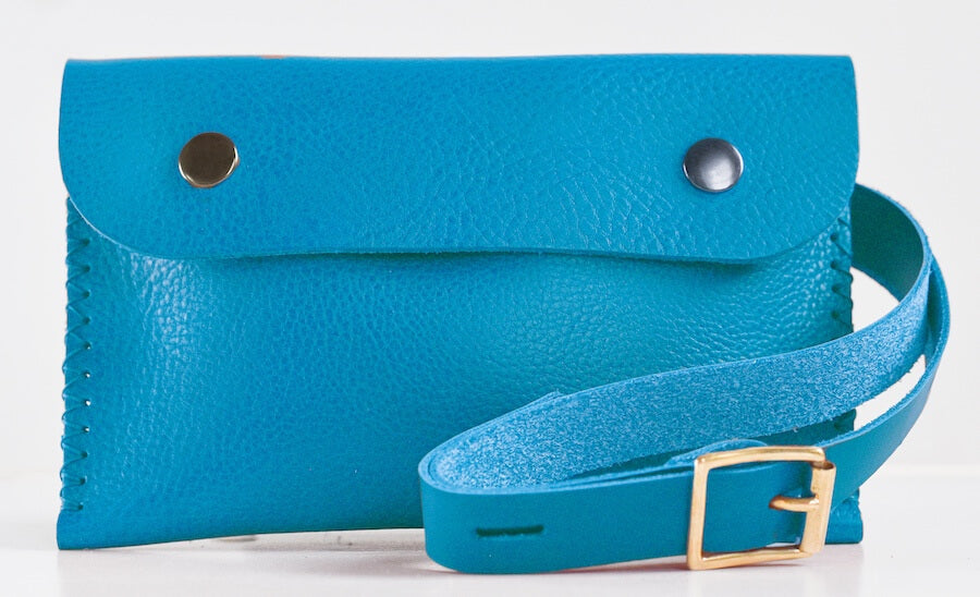 A blue belt bag with a shoulder strap and buckle closure, displayed on a white background.