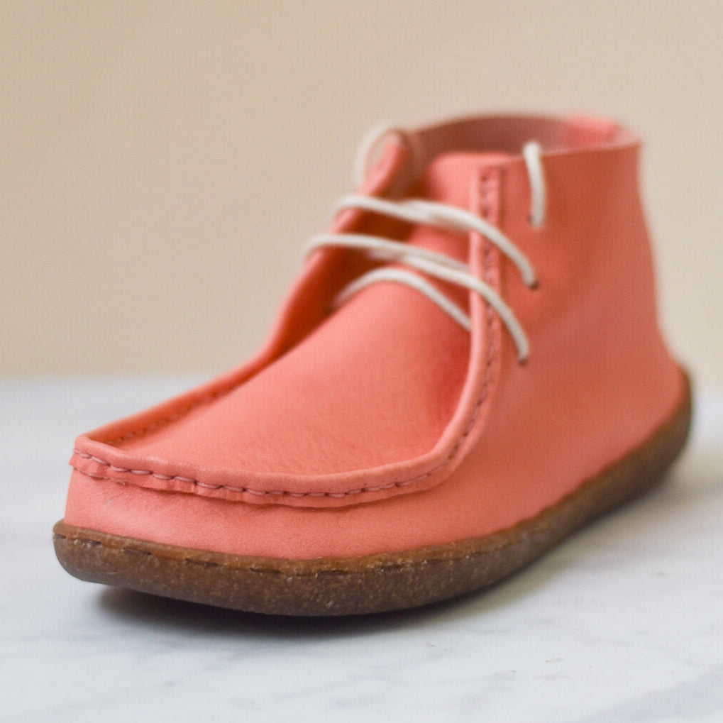 Coral-colored shoe with white laces on a light background
