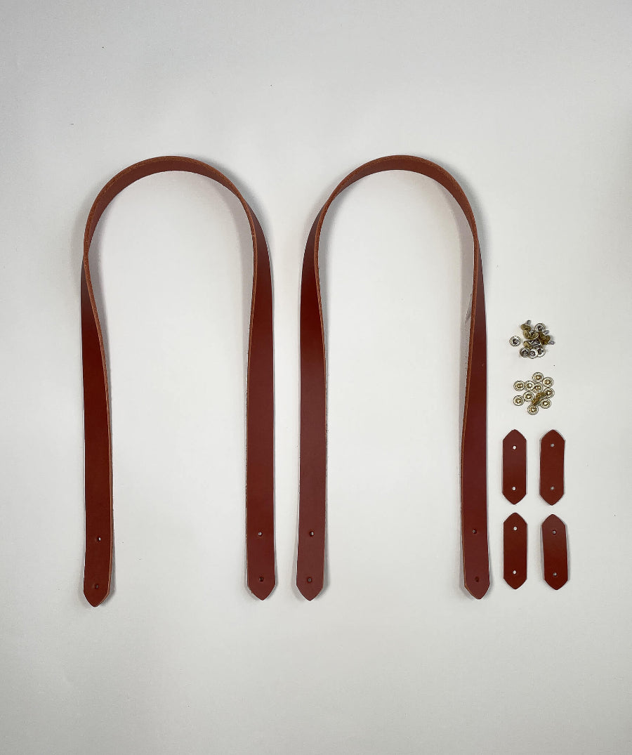 Two brown leather straps with metal hardware on a white background for attaching to handmade bags