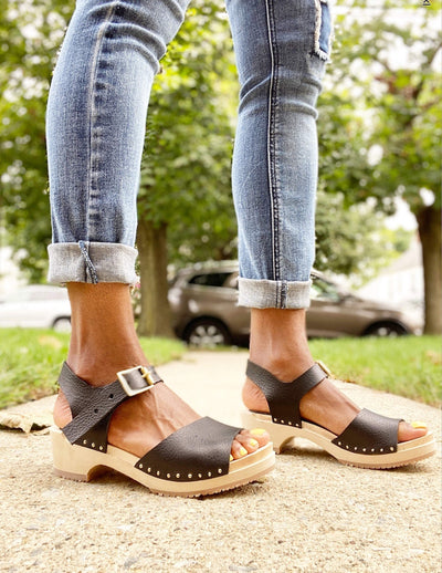 woman wearing jeans and black clogs in park