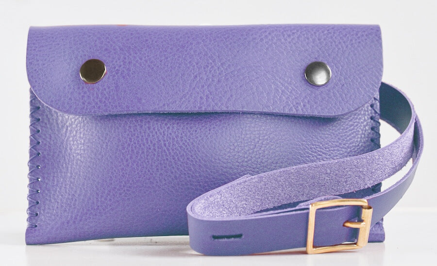 A lilac belt bag with a shoulder strap and buckle closure, displayed on a white background.