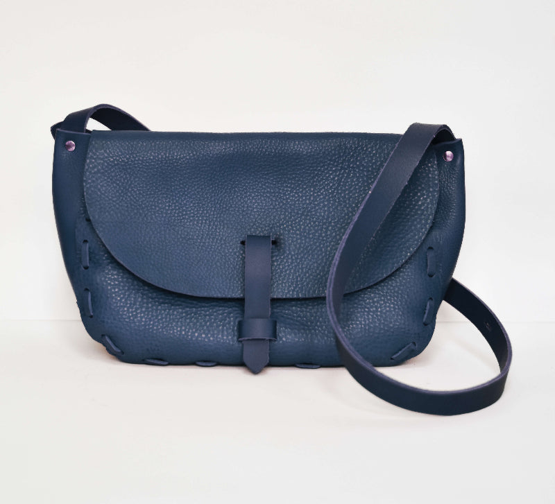 A navy blue leather saddle bag with a simple design and a shoulder strap.