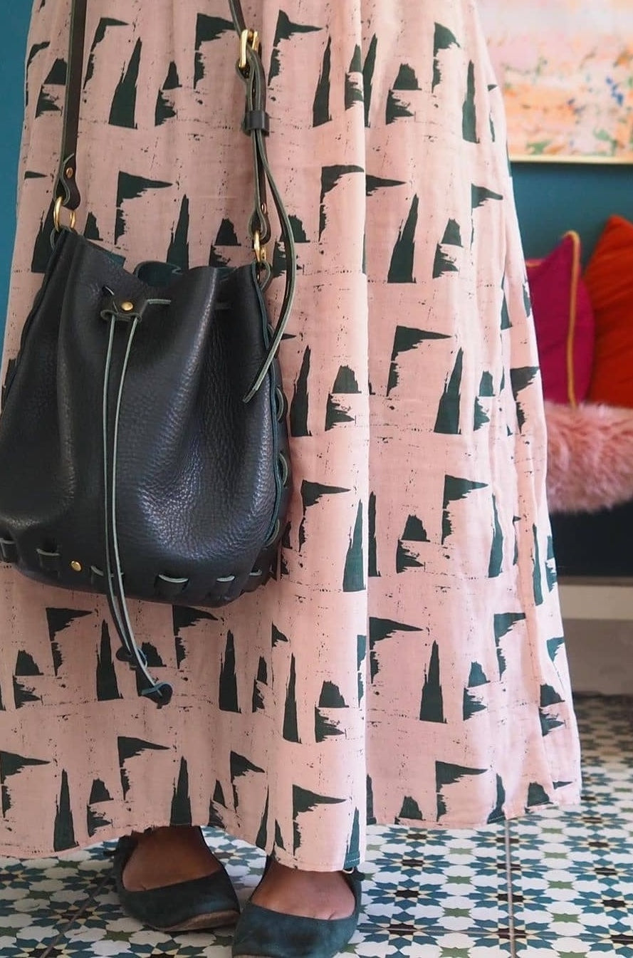 woman in pink dress holding dark green bucket bag she made 