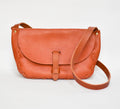 A brown leather saddle bag with a simple design and a shoulder strap.