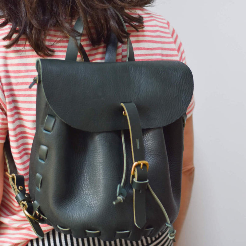 girl wearing dark green leather backpack