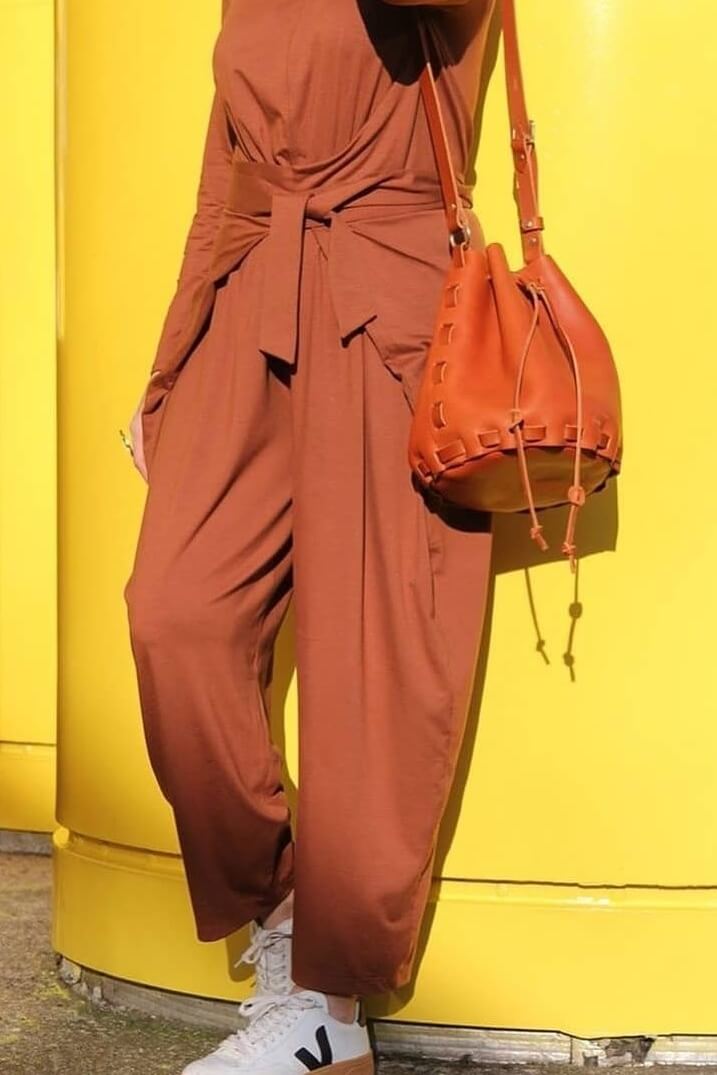 woman wearing tan woven leather bag in front of yellowb building