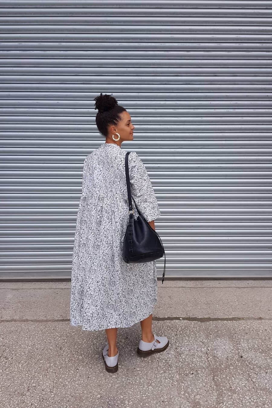 Young woman in white dress wearing black leather bucket bag she made from a kit
